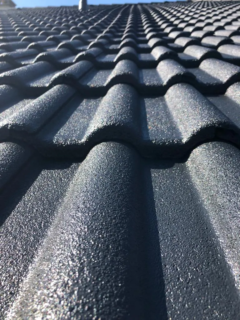 Détail de tuiles à finition anthracite photographiées en lumière naturelle